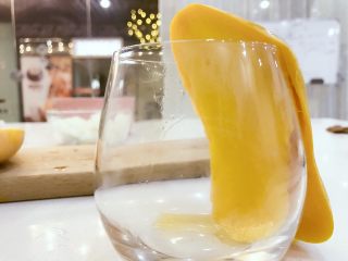 1、宝宝辅食:宝宝芒果饭-12M+ ,用大芒果,沿果核往下切开,可以先去皮再切哈,小芽芒果边缘弯曲程度和杯口和吻合,就直接用杯口去皮啦。