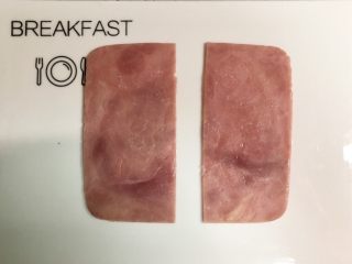 3、小萌猪火腿饭团,把火腿片平均切成两片。