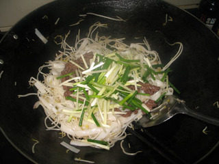 9、干炒牛河,将锅离火,加入牛肉、韭黄、葱段。
