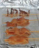 6、美味烤鱿鱼,烤箱预热220度，烤盘铺上锡纸，锡纸上刷层食用油，将串好的鱿鱼排在锡纸上，入烤箱烤20分钟分，中途刷一次腌制鱿鱼时碗中剩余的调味汁，待颜色烤成金黄色，撒上白芝麻继续烤5分即可。