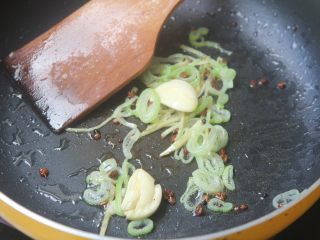 7、爆炒花甲螺,倒入大葱和蒜炒香;