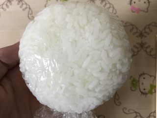 2、招财猫便当/饭团,取100g米饭，用保鲜膜包裹着捏紧，搓圆，压扁，形成圆形饭团