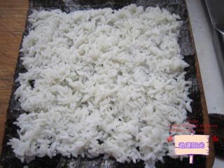 5、花朵????寿司????,将米倒入寿司醋切拌均匀，让寿司醋与饭充分混合渗透。分成两份，取一张紫菜，均匀的铺上一份白米饭