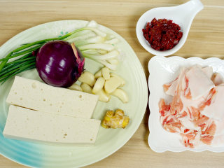 1、干锅千页豆腐,首先我们需要的材料有：带脂猪肉，这里我们选用肥肉，五花肉，腿肉都可以，记得是带脂猪肉就行了（也就是带有肥肉的猪肉）。洋葱，一定要哟，不仅可以使其味道更好，也是防止粘锅的好辅材。调味料就是豆瓣酱，婷姐选用的是自家酿制的豆瓣酱，超市购买的郫县红油豆瓣酱也可以。