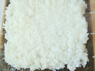2、寿司,寿司帘洗干净，放在干净的菜板上，然后取一张海苔铺在寿司帘上，然后将米饭均匀的铺在海苔上，不要太厚，大约5cm厚度就可以