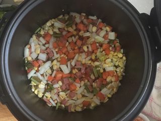 3、电饭煲火腿煲仔饭,将准备好的胡萝卜丁，玉米粒，娃娃菜根部，菠菜根部放入锅中翻炒，炒热即可。