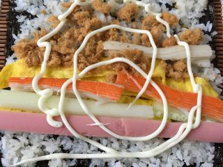 4、寿司,然后把准备的材料铺在糯米上面，挤上沙拉酱、就可以开始卷了，一定要卷紧。