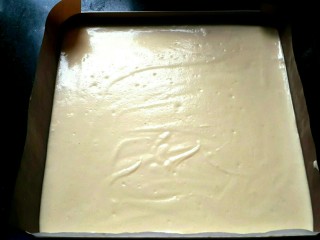 9、芒果蛋卷,倒入垫好油布或油纸的模具中。用刮板将表面刮平。轻震几下，把大气泡震出