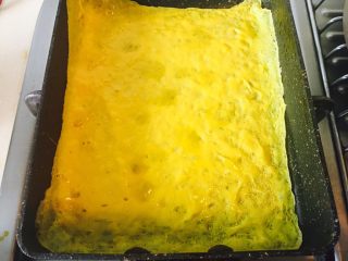 8、油条寿司卷,翻一面,再烘一下。凝结住就好。火开焖饭的火,太大容易焦。如果翻不好,可以把蛋皮倒在盘子里,再通过筷子和手,继续把另一面,放到锅里烘一下就好。大概几十秒时间。烘的时间,根据蛋液倒多少在锅里决定。蛋液倒多了,时间适当增加20秒。烘好的蛋皮,会厚一点。