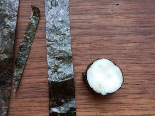 7、小兔子拔萝卜—儿童营养便当,将烤紫菜剪成宽度适当的条,将山药泥在手中捏成扁的圆柱形,用烤紫菜包住,捏成小兔子头部。