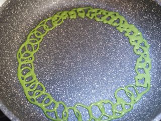 28、彩虹蕾丝蛋饼,开火，用最小最小的火。先在锅的最外圈挤上一圈面糊，像画奥运五环那样挤，一圈套一圈