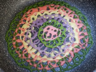 32、彩虹蕾丝蛋饼,好了，最终挤到中心处就完成啦。表面的面糊凝固就可以取出了，不要煎火大了，变成干脆面啊哈哈，开玩笑的，煎制单面就可以哦，不要翻面。