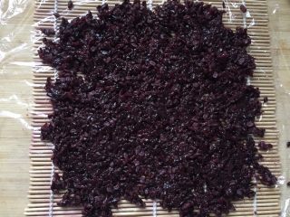 4、快手早餐－健康粢饭团,在案板上铺好卷寿司的珠帘，上面铺一张保鲜膜。米饭混入少量寿司酱油拌匀，均匀地铺在保鲜膜上，可以用平铲整理一下。