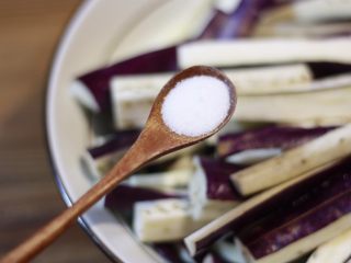 2、下饭菜????肉末茄子,茄子切条盛入容器中,加入一小勺盐,用手将茄条翻拌一下均匀沾上食盐,放置一旁备用。