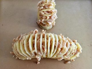 10、风琴土豆,烤好的土豆去锡纸,放进烤盘。利用小水果刀把羊肉塞进土豆片中