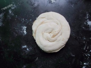 4、自制手抓饼,早饭又多了个选择,从一头边抻边卷，盘成一团。将整形好的饼坯团松弛20分钟后，擀成薄饼。