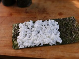 7、炸虾寿司卷,接着整张海苔从中间剪开取一半，在半张海苔上铺上2/3的醋饭；