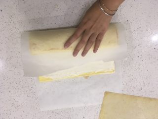 17、经典瑞士卷（原味）,用手拉起牛油纸，顺着奶油的厚度把蛋糕体往里卷。把蛋糕体收进去，记得动作要轻柔哦！