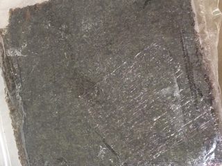 2、翻转樱花寿司,放上一片紫菜，紫菜粗糙面朝自己，光滑面朝席子