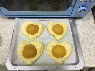 13、黄桃椰蓉心形面包,发酵后的体积是原来的1.5倍大小，取出发酵好的面团，刷上薄薄一层全蛋液，均匀撒上准备好的黄油椰蓉，把黄桃果肉放在面团中间，往里按压，将黄桃固定住