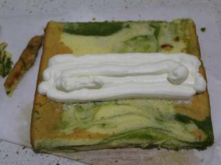 20、抹茶双色蛋糕卷,把对着自己和挨着自己的两头的边修整一下，奶油挤在中间，也可以全部抹上，因为很小，我是徒手卷的。用油纸包好放进冰箱冷藏定型，再拿出来切。