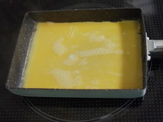 2、饭团便当,热锅入油(硬币大小吧)用厨房纸抹匀,先倒进去一层蛋液,烙熟之后由把手这边开始卷,卷成卷。