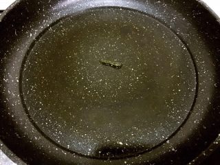 3、培根胡萝卜鸡蛋卷饭团,开小火,平底锅当中滴几滴油,用锅铲背面将油抹开,涂满锅底一圈