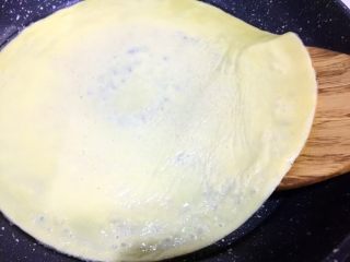 5、培根胡萝卜鸡蛋卷饭团,用锅铲轻轻从蛋皮边上掀起,使整张蛋皮脱离锅底,动作一定要轻柔一些,以免蛋皮破损