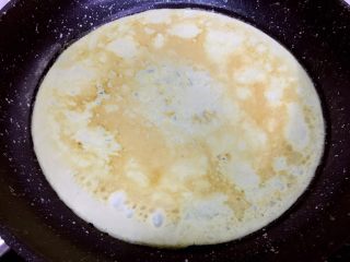 6、培根胡萝卜鸡蛋卷饭团,然后用锅铲将蛋皮快速翻面,稍烘几秒