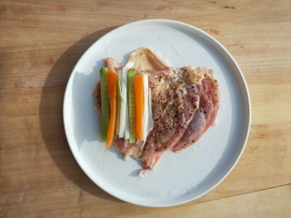 5、黑胡椒烤蔬菜鸡腿卷,平摊开鸡腿排，依次放胡萝卜条，黄瓜条，葱段。