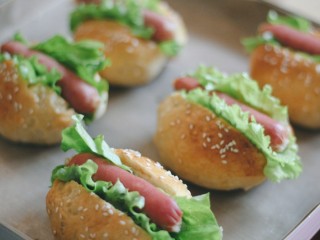 9、美式香肠热狗,香肠可蒸可煮可烤，生菜洗净撕成合适的大小，面包中间竖着切一刀，但不要完全切断，夹入香肠和生菜。