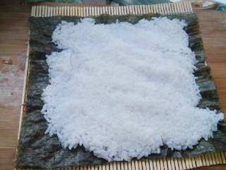 5、食寿司卷——剩米饭的华丽转身,在寿司帘上放上寿司紫菜,将米饭铺平,不要压饭粒,尽量保持饭粒完整,松软,四周稍微留一点边。