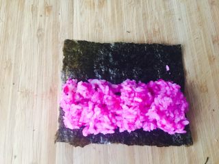 5、童趣寿司,取1／2紫菜。这时的紫菜宽度，也是和山药宽度同宽。把饭团包起来。