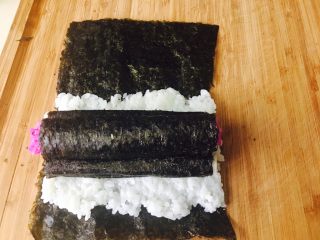 6、童趣寿司,这时就可以做组合了。取一张没裁剪过的紫菜，宽度同山药同宽。把米饭铺满1／2。放两根卷好紫菜的山药，再把卷好的红色饭团放上面，再卷起来即可。