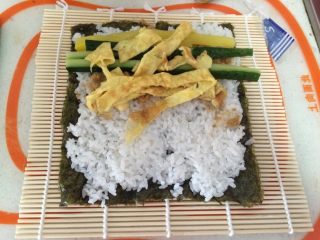 3、寿司,在铺好的米饭上依次放上肉松，黄瓜条，鸡蛋皮，萝卜条等你喜欢吃的东西。