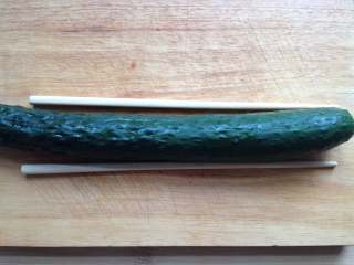 2、蓑衣黄瓜,黄瓜洗净后放在熟食案板上，两边各放一根筷子（如图，这样可以避免把黄瓜切断）