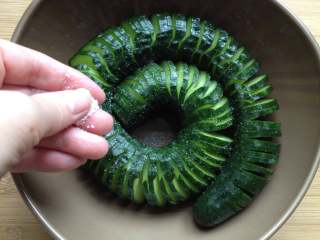 5、蓑衣黄瓜,切完后就可以随意拉伸哈，然后放到大碗里，把盐均匀撒在黄瓜上，腌制1小时左右