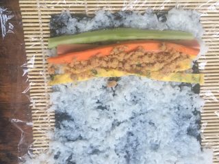 6、爱心寿司,竹帘最下面，第二保鲜膜，第用饭勺把糯米饭薄薄的压在海苔上，注意要薄薄的哦，第三食材分别放在糯米饭的一边，注意：糯米饭不要铺的太满，铺食材不要太多，第四就是卷起来，这个卷真的是需要点技术的，