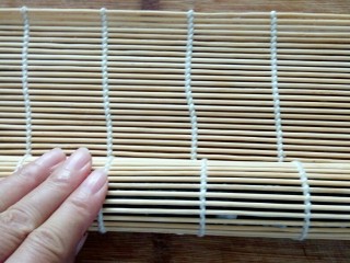 8、培根寿司卷,在用竹帘裹上，幹几下，使寿司卷更紧实