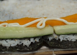 5、青瓜芒果寿司,在底部约1/5处放上青瓜和芒果，挤上沙拉酱