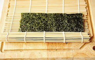 4、小花寿司,借助寿司帘卷起，使海苔紧紧包住米饭；