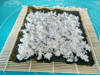 12、金枪鱼饭卷,将米饭均匀的涂在紫菜上，上面的边留宽点，不涂米饭，用于封口。
