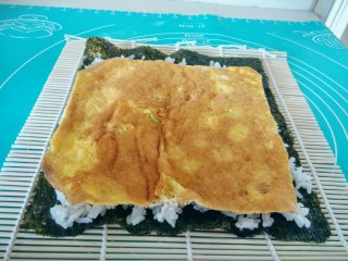 13、金枪鱼饭卷,将鸡蛋饼的四边切掉一点，成四方形，铺在米饭上。