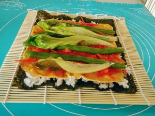 15、金枪鱼饭卷,将生菜在开水中烫一下，马上捞出，控干水份，取3片铺在胡萝卜丝上面。