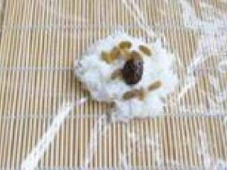 5、玫瑰丝饭,案板上铺寿司帘，然后再铺上保鲜膜，先糯米饭均匀的铺在面上，然后在糯米饭上均匀的撒一层葡萄干、蜜枣。