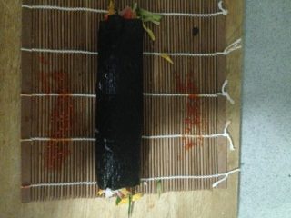 4、紫菜包饭,将竹帘卷起，拉紧，如图