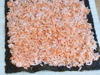 3、韩式紫菜包饭便当,将寿司紫菜铺在寿司帘上，把米饭铺匀。