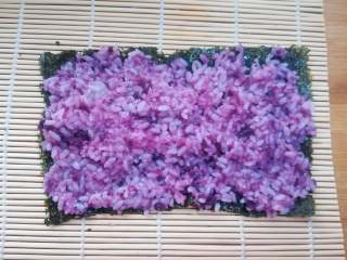 7、紫薯寿司,把拌匀的紫薯米饭均匀的铺在紫菜上,紫菜的两端也要有米饭粒。如果觉得米饭比较粘,可以用勺子沾水,有勺背来把米饭推均匀。用手来操作的话,也可以在手上抹些凉开水,或寿司醋防止黏手。