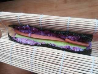 9、紫薯寿司,用手托起卷帘,让两端粘合在一起。因为米饭有粘性,会很自然的粘合在一起。