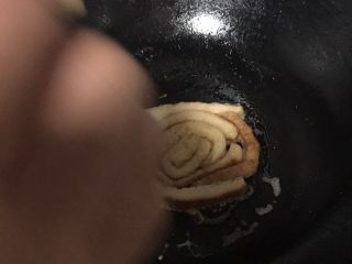 5、#甜味#香浓牛奶吐司年轮圈,放入锅中煎，煎的时候来小火，用筷子卷出形状，小心烫手哦。